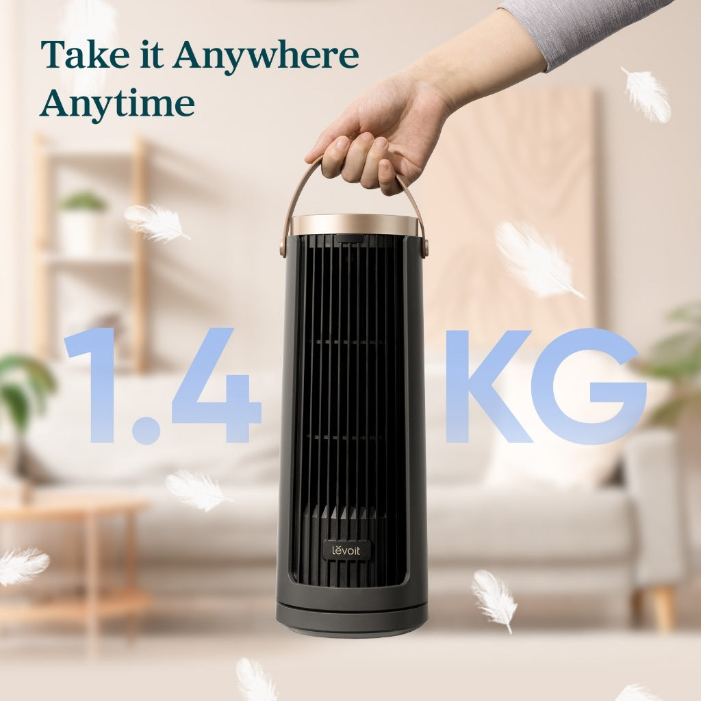 Black tower fan being carried by its top copper handle