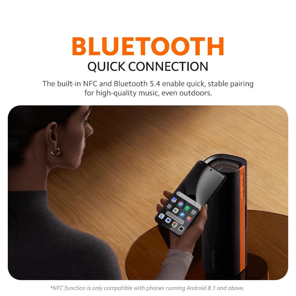 Black Bluetooth speaker with orange trim next to a smartphone for quick connection