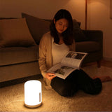 White bedside lamp glowing on the floor beside a person reading