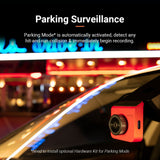Red dash cam rear camera mounted inside a car near the windshield at night.