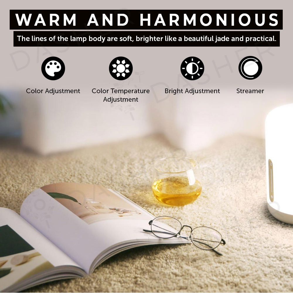 White bedside lamp with warm glow on a carpet near an open book