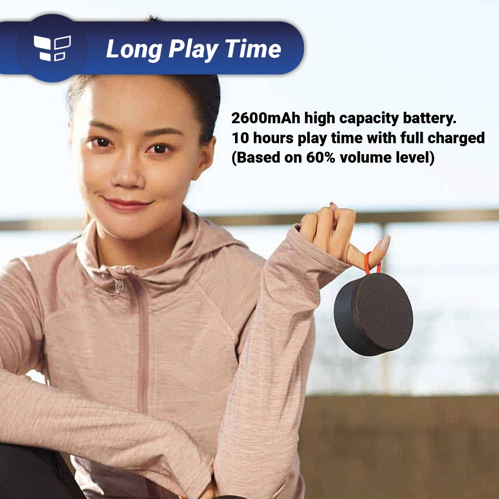Mini outdoor Bluetooth speaker, round dark body with orange carry loop, held near face