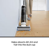 Upright vacuum cleaner with brush roller on floor, dust and debris visible