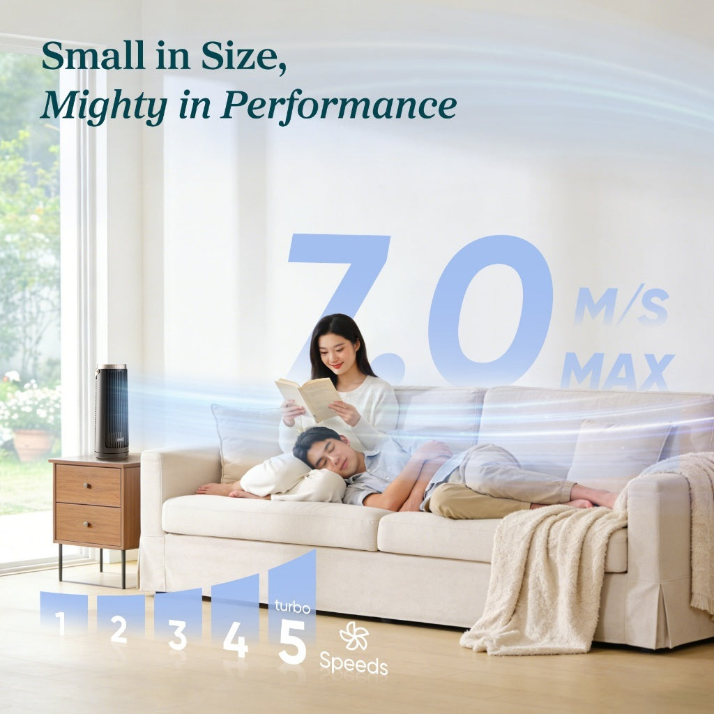 Black portable tower fan on the floor beside a sofa, compact size