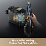 Steam spot cleaner with transparent tanks and hose held by a hand