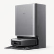 Silver robot vacuum dock with dark self-emptying station and charging robot